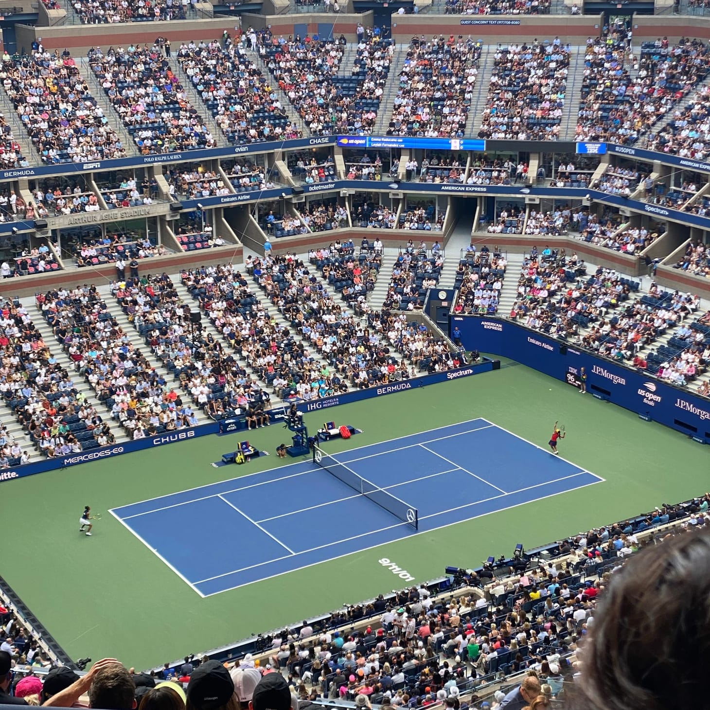 a photo of a packed stadium and a tennis court, Emma Raducanu and Leylah Fernandez in Arthur Ashe for the 2021 US Open women's final