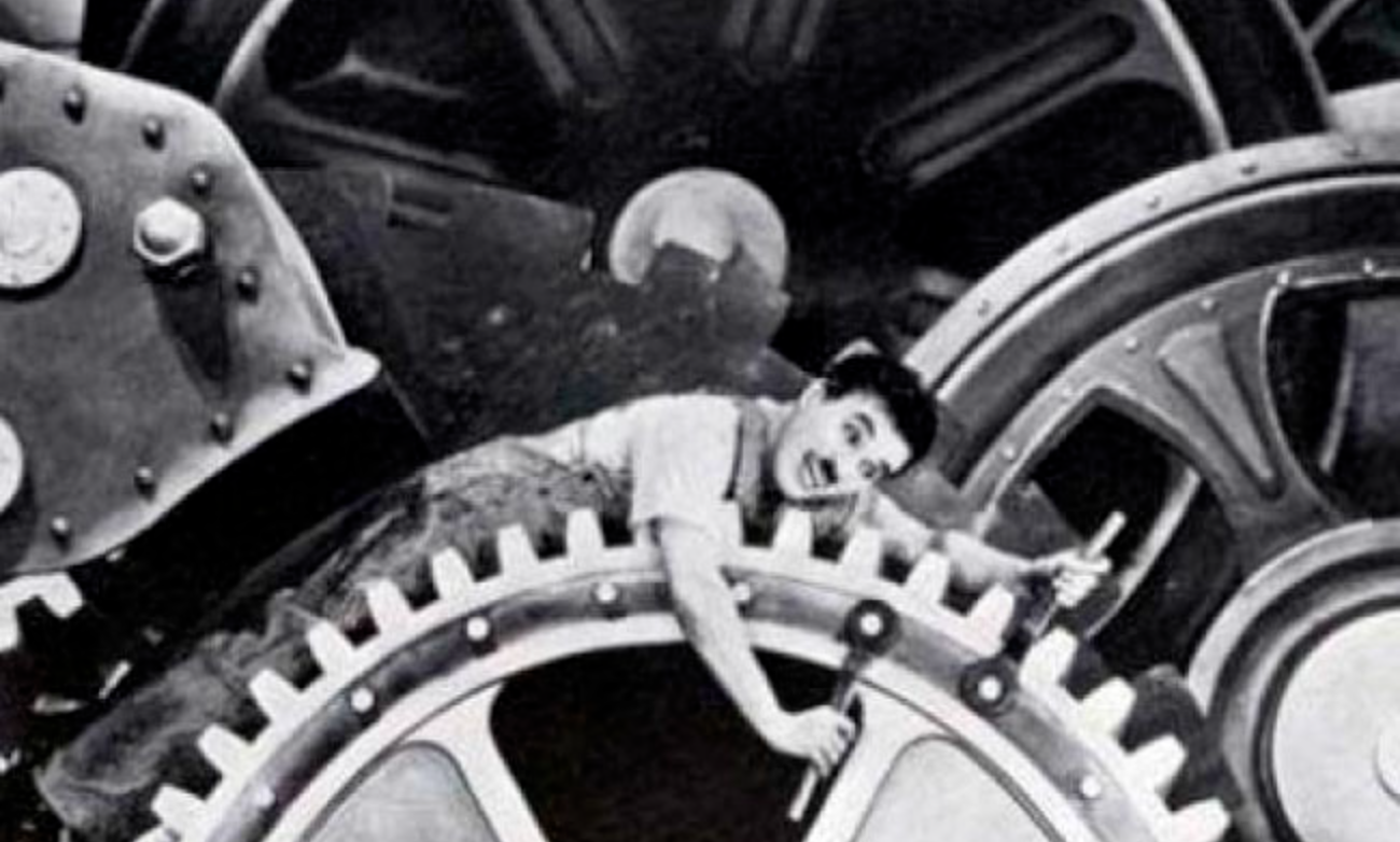 Charlie Chaplin caught in the cogs of a machine he's trying to work on