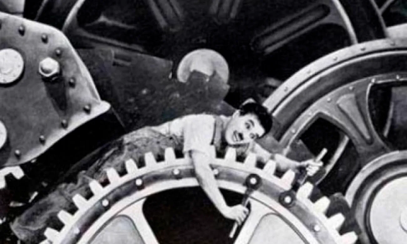 Charlie Chaplin caught in the cogs of a machine he's trying to work on